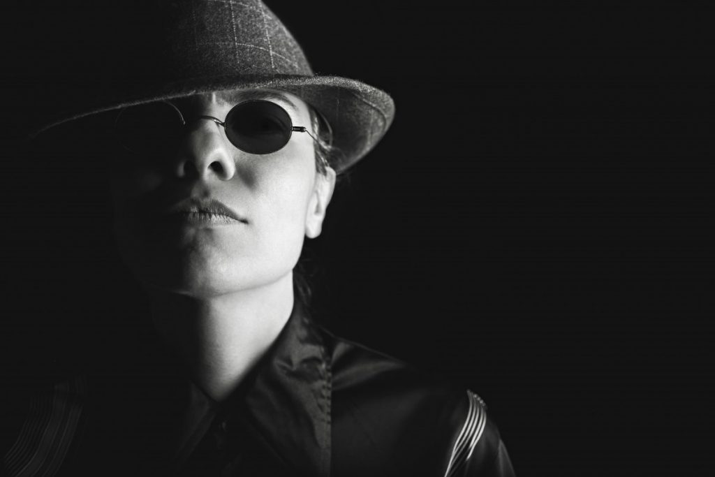 Schwarz-weißes Porträtbild eines Mannes mit Hut und Sonnenbrille